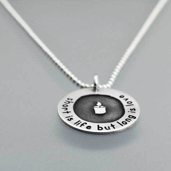 Side view of silver etched necklace with a candle and "short is life but long is love"; all proceeds donated to the Newtown Memorial Fund
